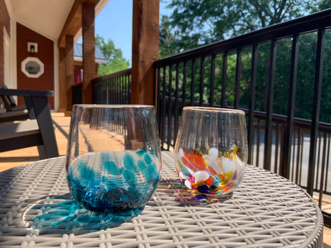 An Ocean Wave and Multi hand blown wine glass rest on a patio table.