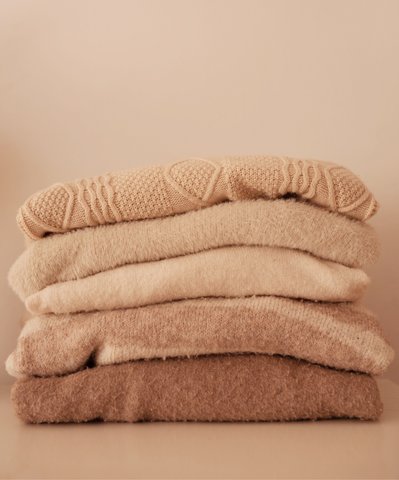 A pile of beige cozy sweaters