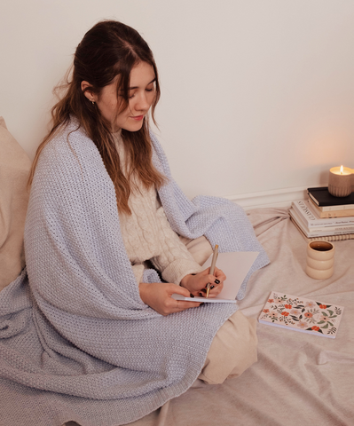 A cozy girl writing in her goals in her cute floral notebook by Mimi & August