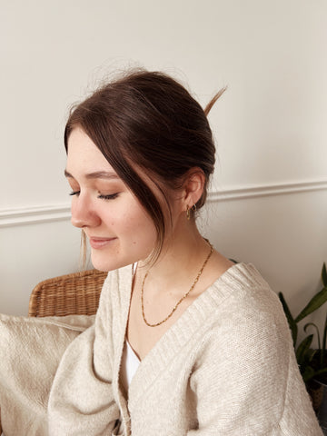 A girl with her brown hair up looking down and smiling