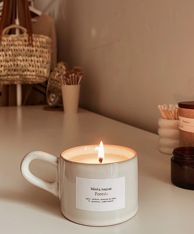 Foresta 5.5 oz Mimi & August candle burning in a cozy room