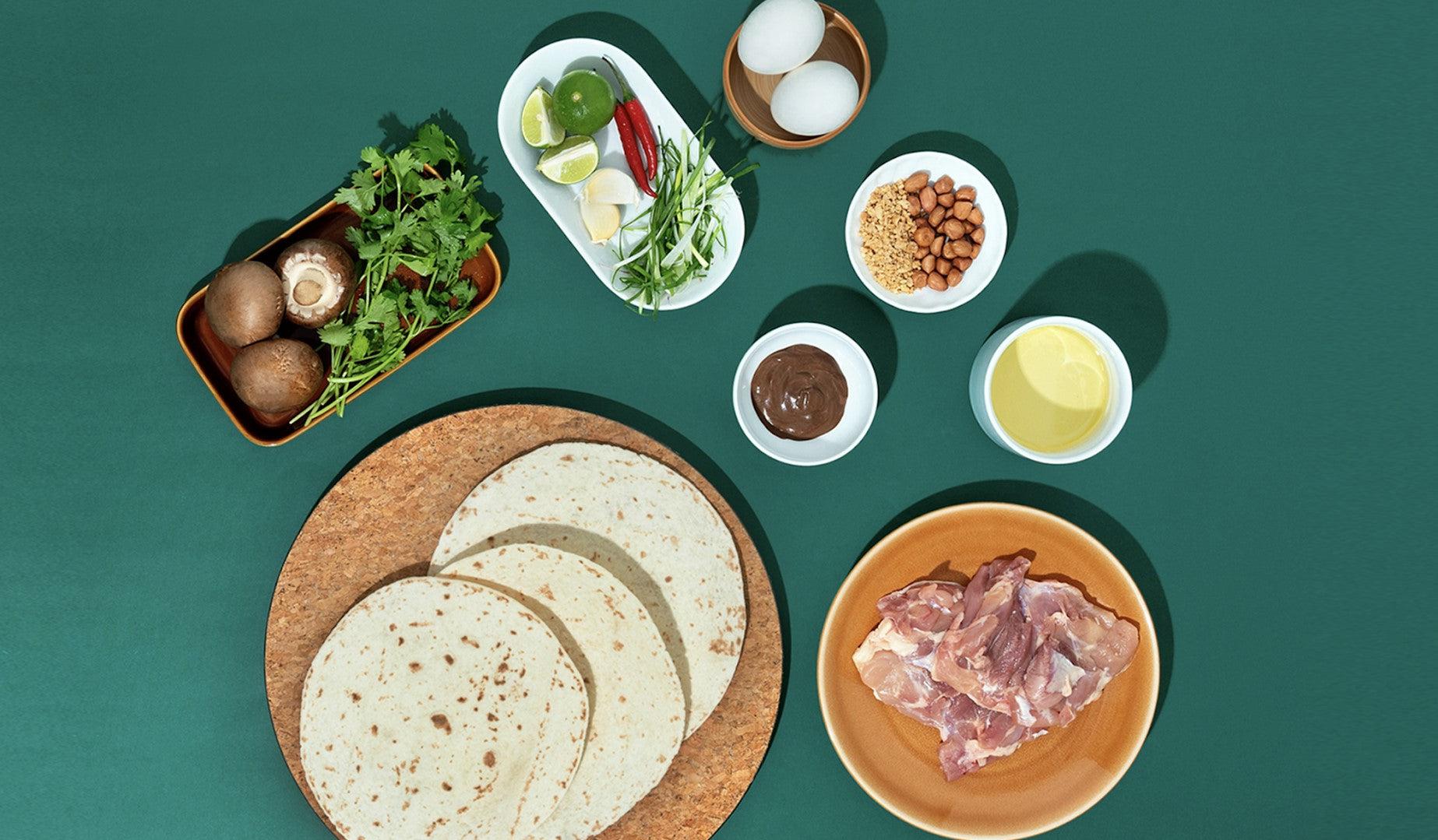 All ingredients for making Pad Thai tacos arranged on a vibrant green table