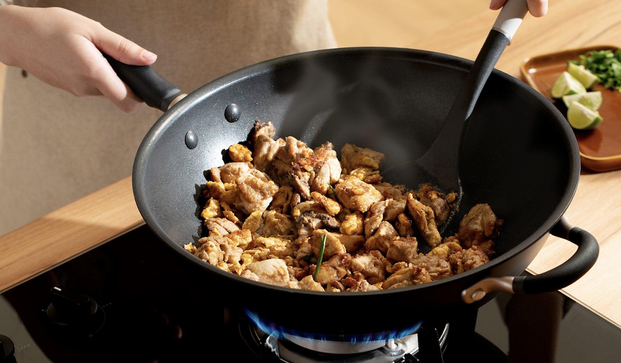 Frying chicken thighs with all ingredients in a Meyer nonstick stirfry while using a turner