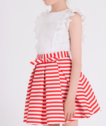 ecru blouse with ruffled front and sleeves, red and white striped skirt with a little bow on the waist