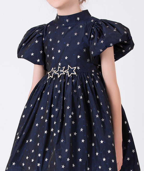 navy dress with short balloon sleeves, silver star prints and shimmering star brooches on the waist