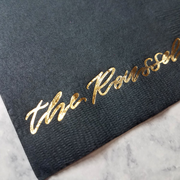Gold foil calligraphy on black paper cocktail napkins, by inviting.