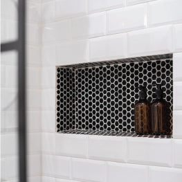 A built-in shower niche with shampoo and conditioner sitting in it