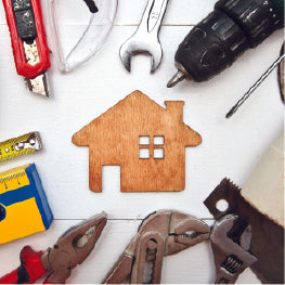 Tools laid out surrounding a cut out wood shaped like a home
