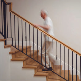 A wood staircase with a blurred senior walking up it
