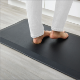 A woman's feet on an anti-fatigue floor mat in a kitchen