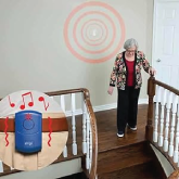 An elderly woman walking downstairs to go to the front door after hearing her doorbell alarm