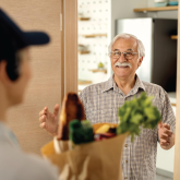 An elderly man getting groceries delivered to his home