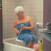 An elderly woman using a handheld shower spray in her bathtub