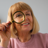 An elderly woman looking through a magnifying glass