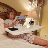 An elderly woman sitting in bed with an overbed table