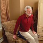 An elderly man using a lifting seat to stand up
