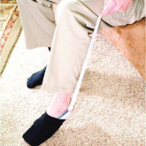 An elderly man using a sock aid to put on socks