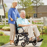 An elderly man being pushed in a transport chair