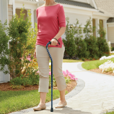 An elderly woman walkin with a caneg