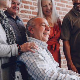 An elderly man in a wheelchair surrounded by people