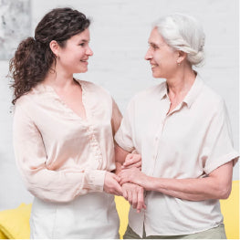 A younger woman holding an older woman smiling at each other