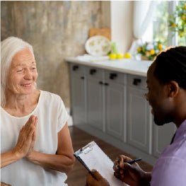 A home health care aid with paper looking at a senior woman