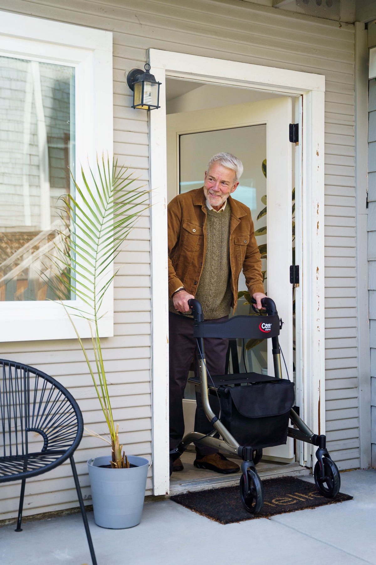 A man peeking out a door using the Carex Crosstour Rolling Walker