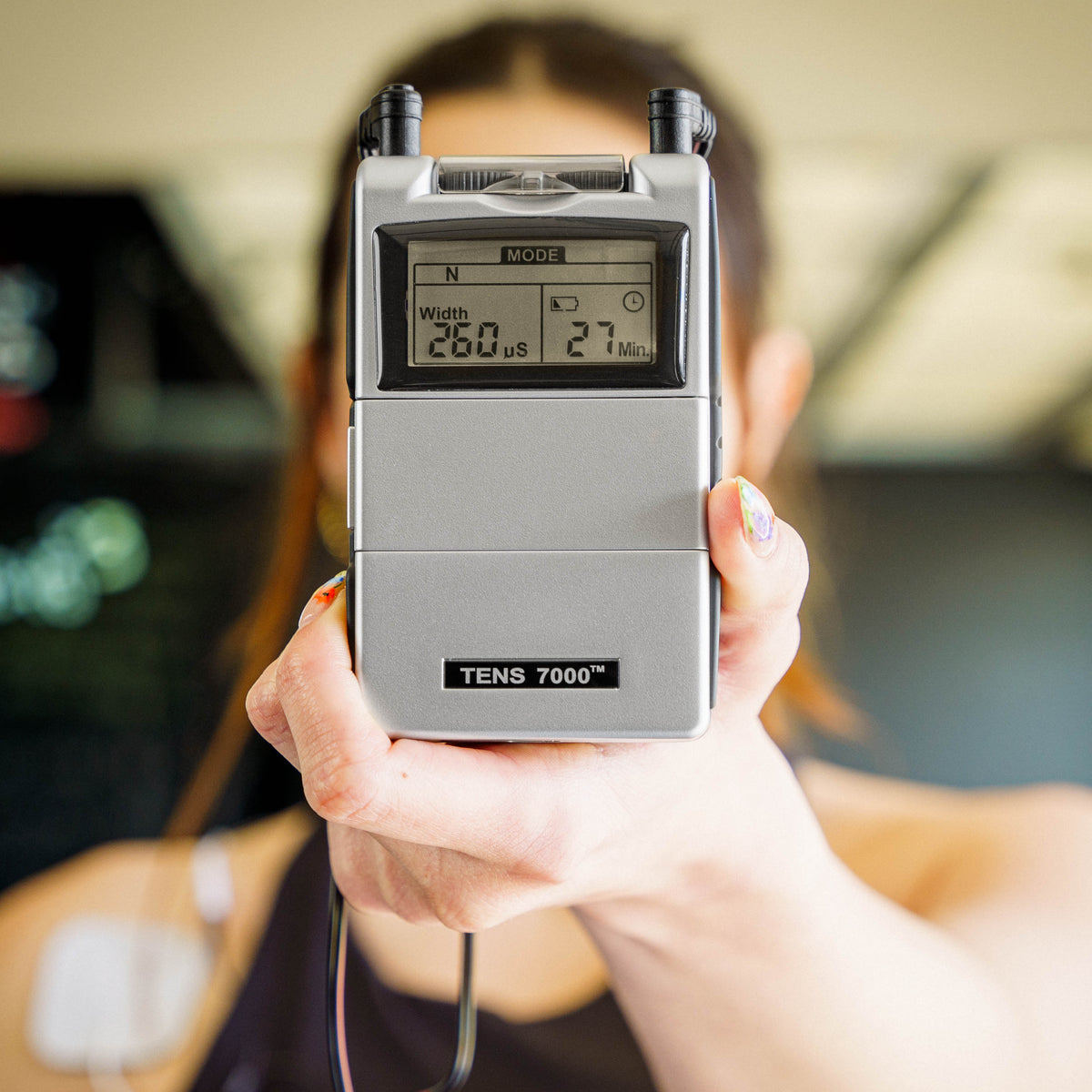A woman holding the TENS 7000 Rechargeable TENS and EMS Combo Unit
