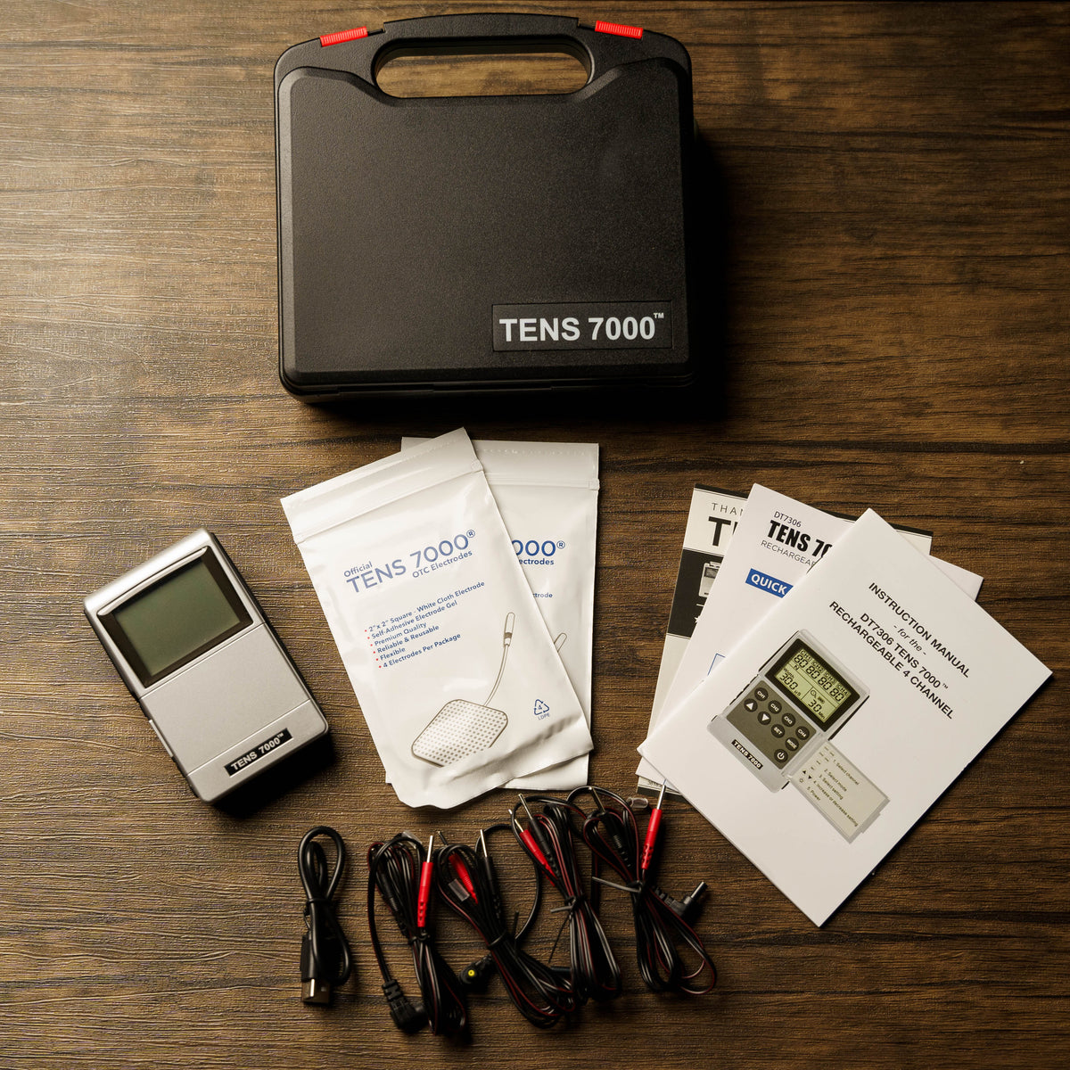 The TENS and EMS combo unit with everything included on a wood surface
