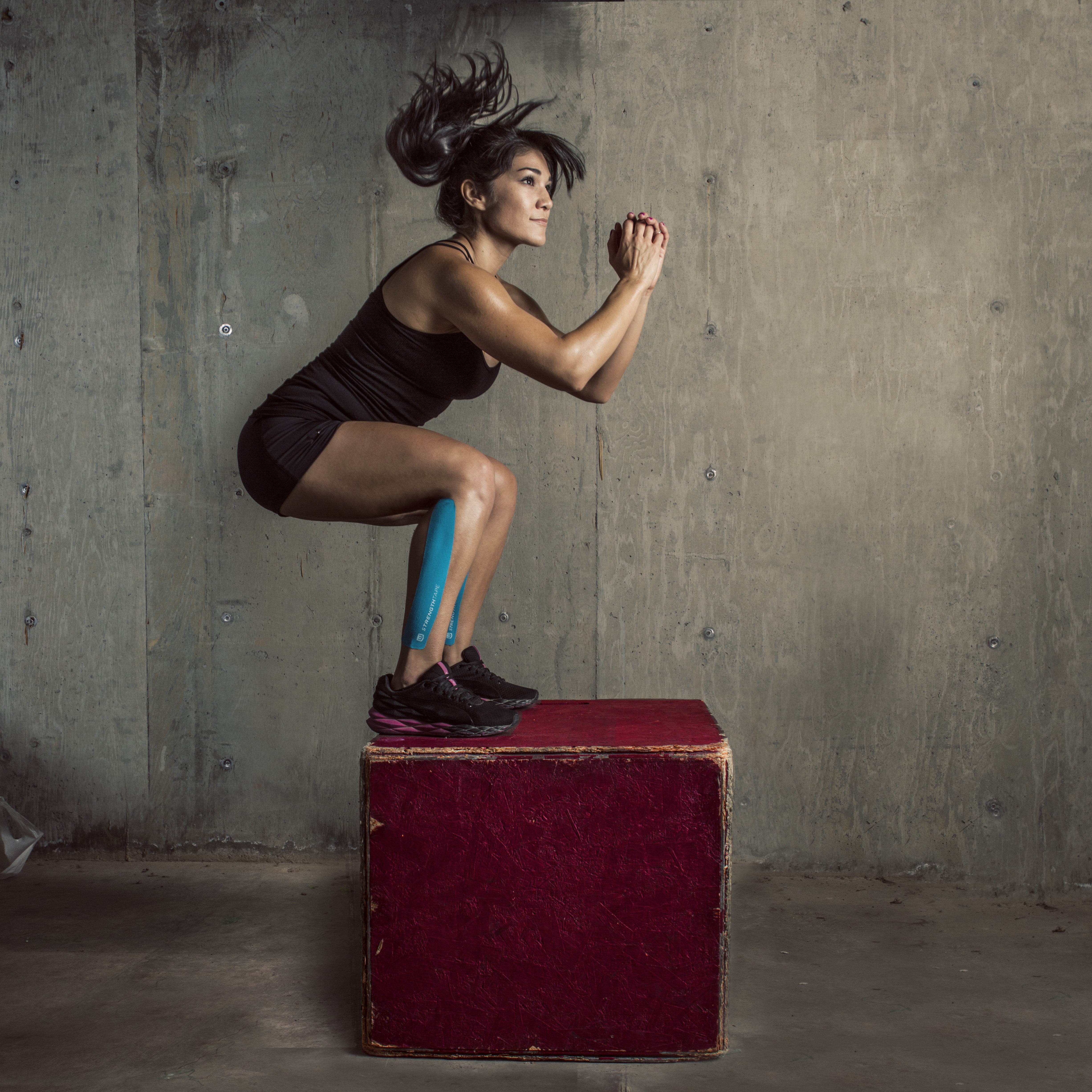 A woman jumping on a box with kinesiology tape on her leg