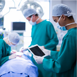 A surgeon holding a tablet in a surgery room