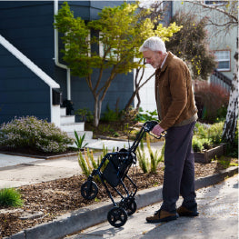 A man using a rollator to step over a curb outside