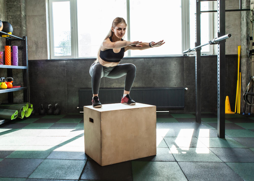 A woman doing a box jump in a gym