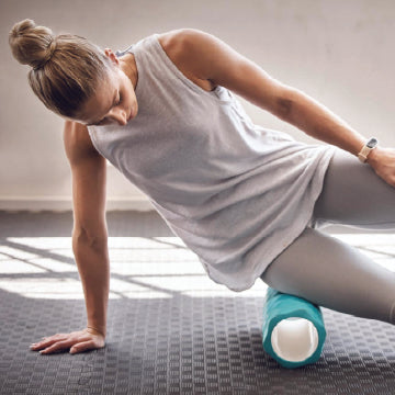 A woman using a foam roller on her outer hip which puts pressure on bursae and aggravates hip bursitis