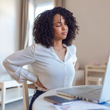 A woman sitting at a table experiencing hip bursitis pain from prolonged sitting