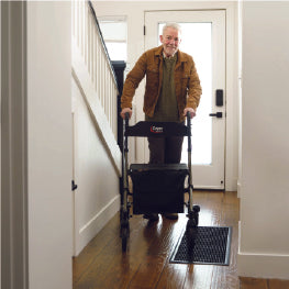 An elderly man walking inside with a rollator
