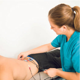 A doctor placing electrodes over the hips of a person for low shock wave energy therapy