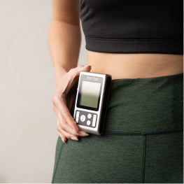 Close up of a TENS unit clipped to a woman’s hip