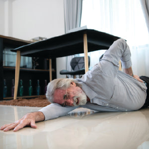An elderly man who has fallen and is holding his hip in pain