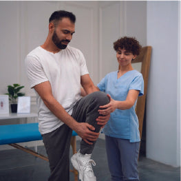 A physical therapist helping a patient stretch their hip