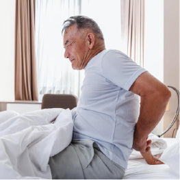 A man sitting up in bed with hip pain