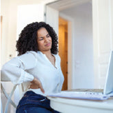 A woman sitting in front of a laptop with hip pain