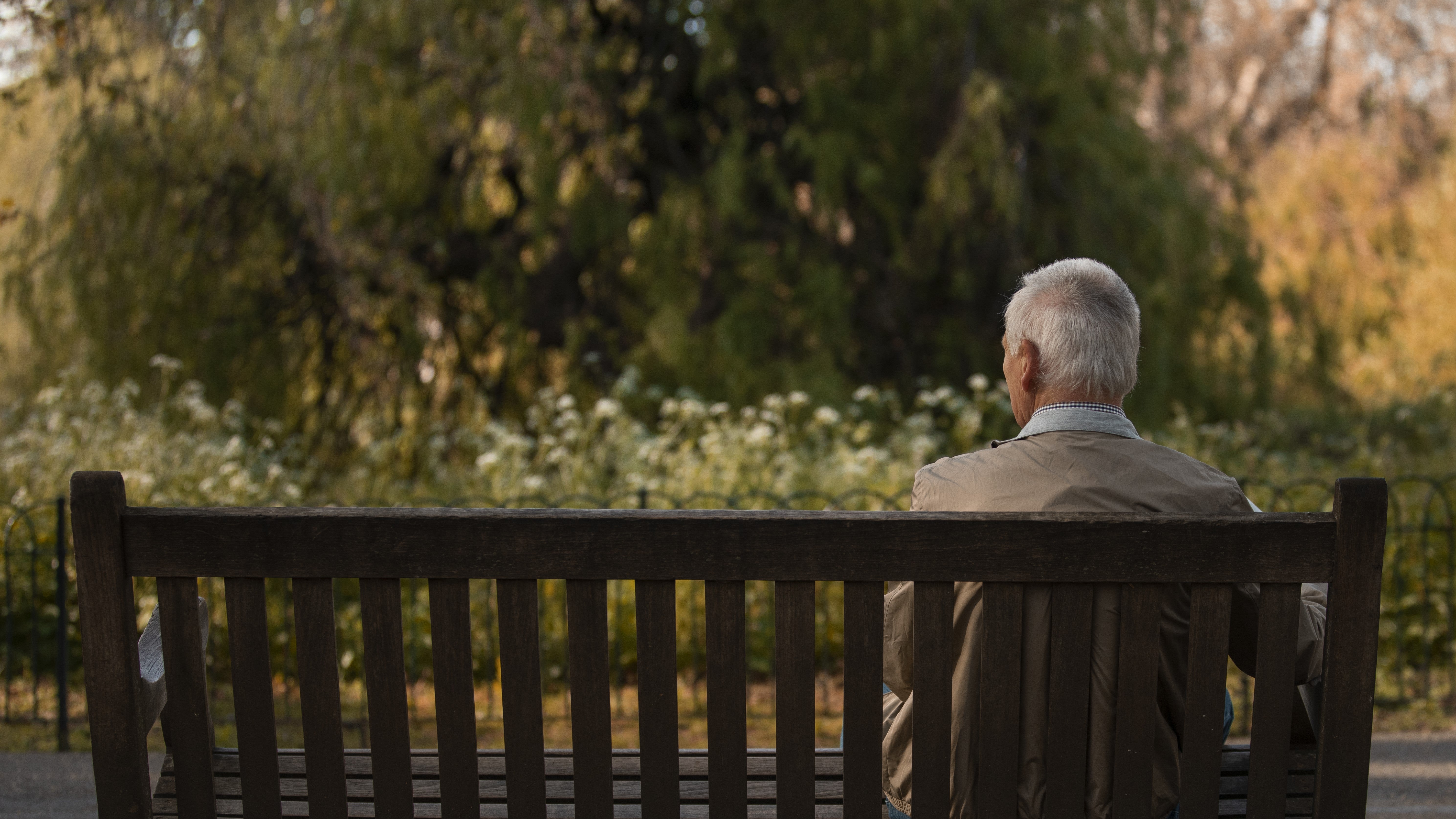 An elderly man sitting on a bench alone