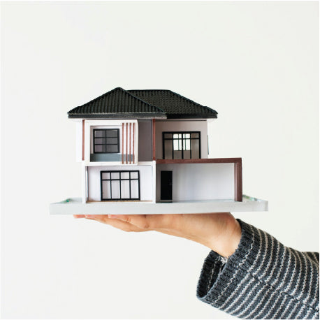 A person holding up a model of a home