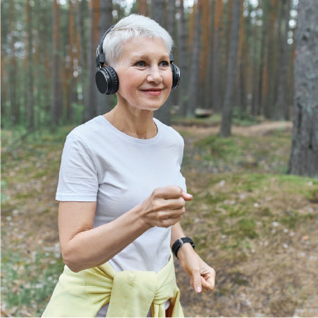 An elderly woman jogging in woods