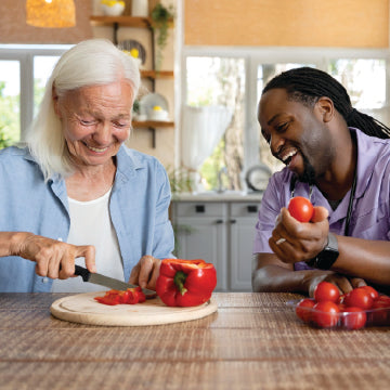 An occupational therapist helping an elderly woman cut vegetables