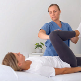 A physical therapist helping a patient stretch their hip