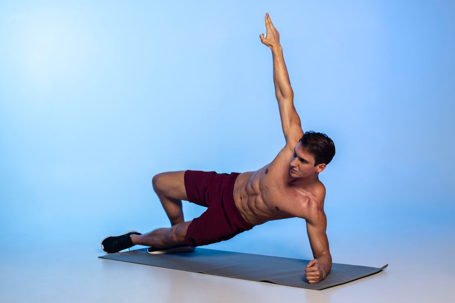 A man doing a side plank on a yoga mat'