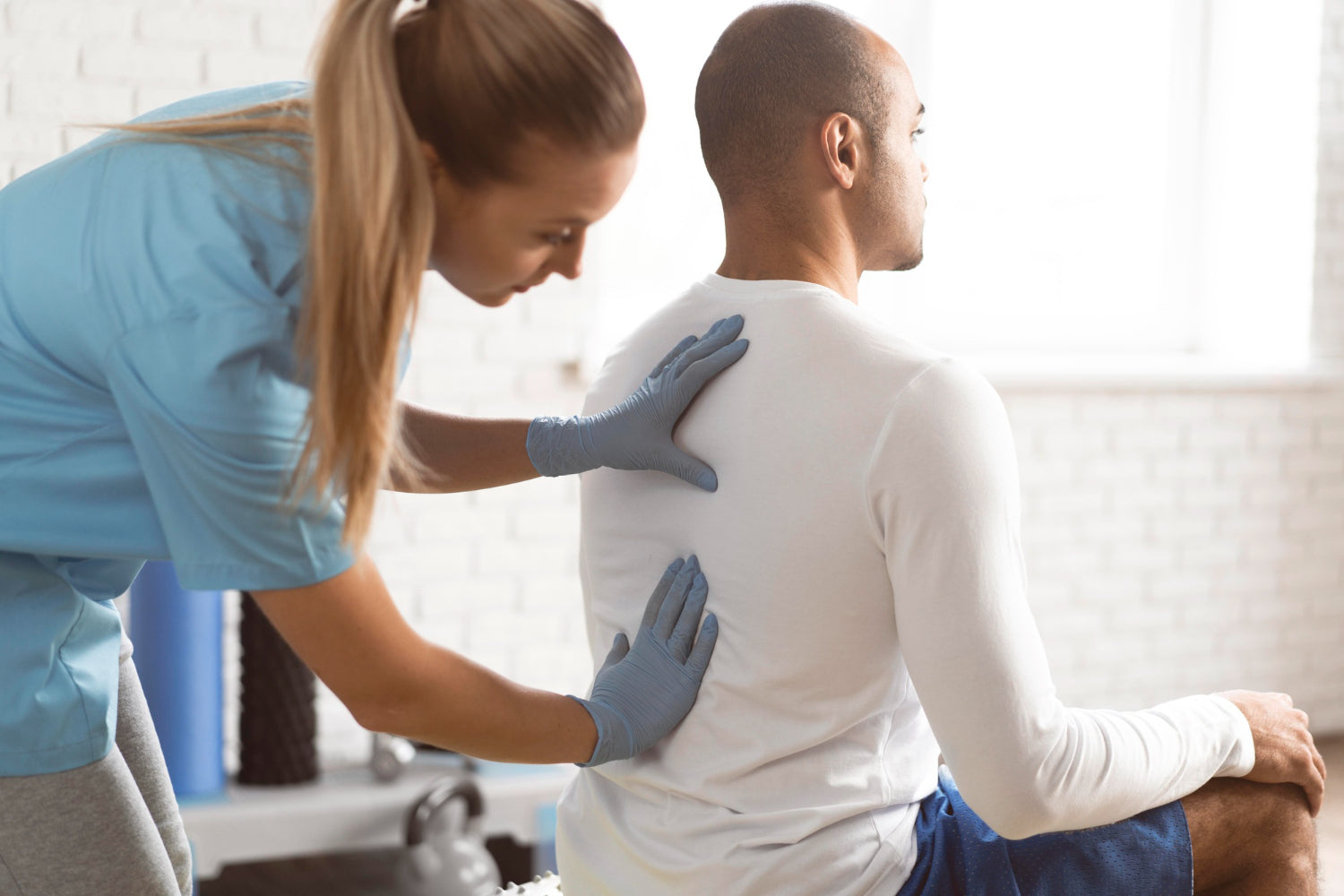 A physical therapist checking a man's back'