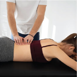 A massage therapist massing a woman's piriformis muscle